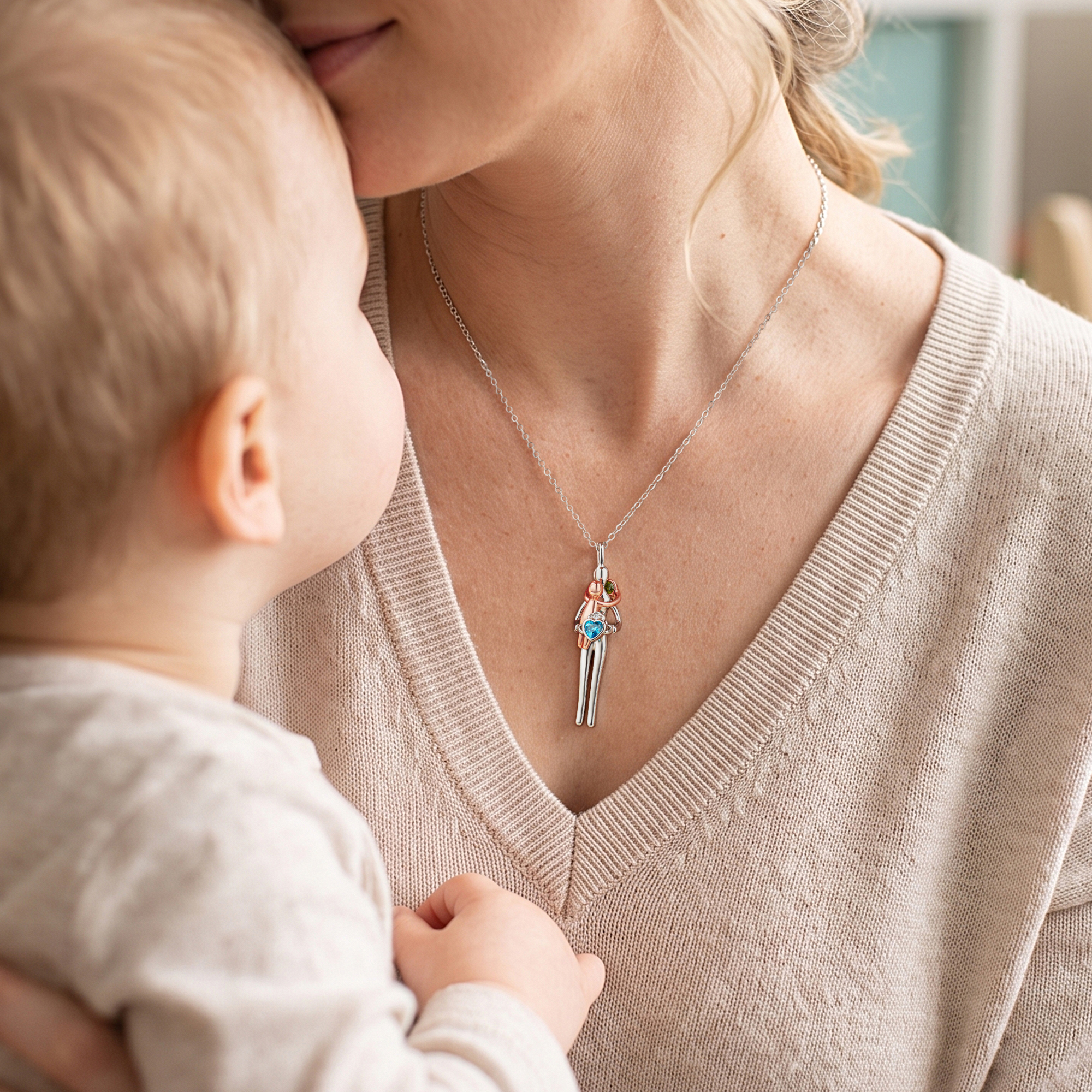 Mother wearing personalized parent and child birthstone necklace while holding baby