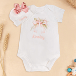 Spersonalizowany, wykonany w 100% z bawełny, miękki kombinezon dla dziewczynki z motywem kwiatowym i kokardką oraz czapeczką z imieniem – prezent na baby shower i urodziny dla noworodka oraz świeżo up 1