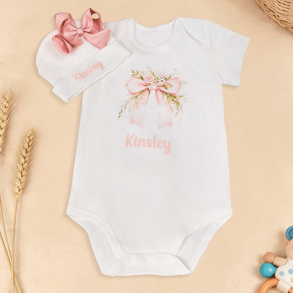 Spersonalizowany, wykonany w 100% z bawełny, miękki kombinezon dla dziewczynki z motywem kwiatowym i kokardką oraz czapeczką z imieniem – prezent na baby shower i urodziny dla noworodka oraz świeżo up